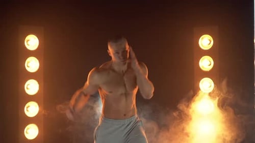 Männlicher Boxer schlägt in die Kamera und zur Seite, athletischer Mann ohne Hemd, der ohne Handschuhe auf Smoky