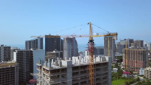 Grúa de construcción en el sitio de construcción con montañas y ciudad como telón de fondo.