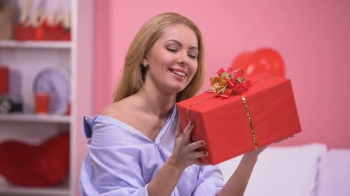 Woman Holds a Red Gift Box and Smiles