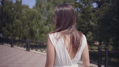 Stylish Woman Walking Through Park on Sunny Day
