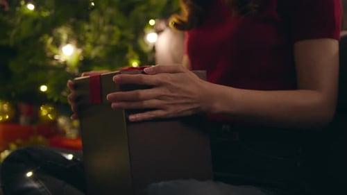 Woman Opens Present Under Christmas Tree at Night