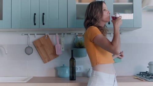 Woman Dancing and Drinking Wine in Kitchen