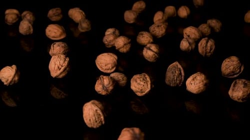 Walnuts Dropping on Reflective Black Background