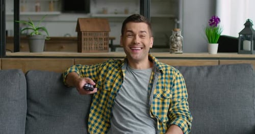 Smiling Man Relaxing on Couch with Remote Control