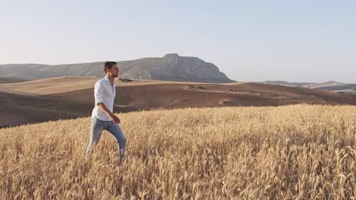 Montanhas bonitas do céu e homem andando em um campo de trigo aberto
