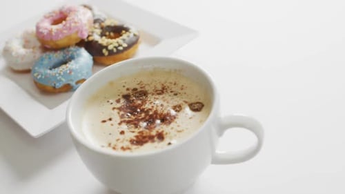 Close Up Coffee and Colorful Donuts on White Table