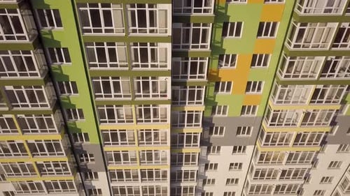 Aerial footage of a tall residential apartment building with many windows and balconies.