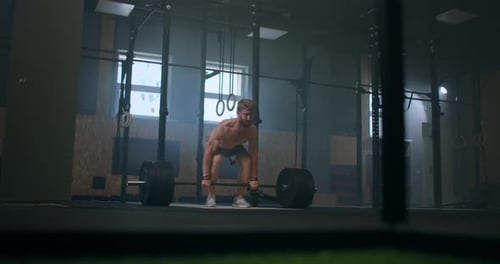 Wide Shot of Young Caucasian Extreme Weightlifting Athlete Man Working Out with Heavy Barbell in