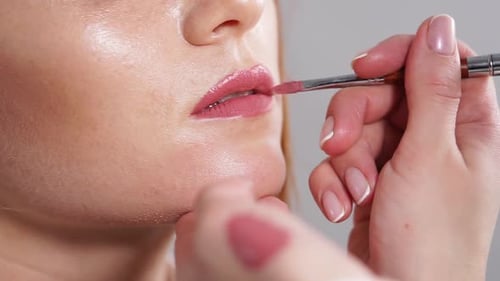 Master Is Applying Lipstick on a Client