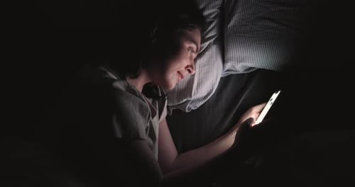 Woman Using Smartphone in Bed at Night