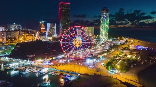 Aerial hyperlapse of Ferris wheel, alphabetic tower, skyscrapers and embankment of Batumi city