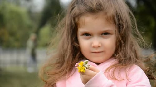 Smiling Child Holds Flowers in Green Park
