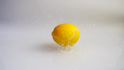 Bright Yellow Lemon Splashing into Clear Water