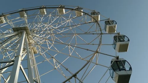 Closeup modern Ferris wheel against blue sky and white clouds