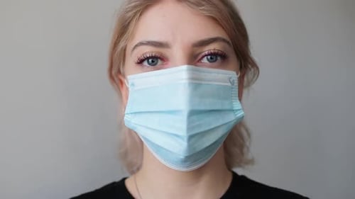 Woman Wearing Face Mask Looks at Camera
