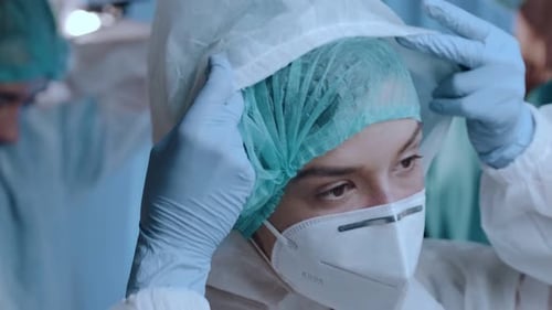 Medical Professional Donning Protective Gear in Hospital Setting