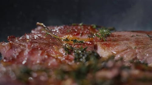 Delicious Steak Cooking with Herbs in Close Up