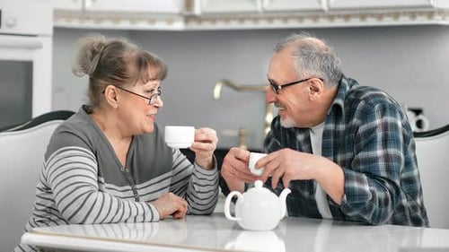 Smiling Middle Aged People Enjoying Friendly Conversation During Coffee Break at White Kitchen