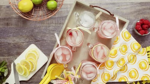 Pouring Pink Lemonade into Jars of Ice