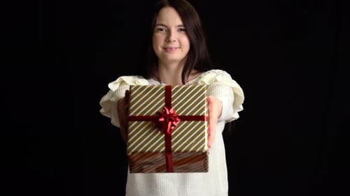Woman Smiling and Offering a Gift on Black