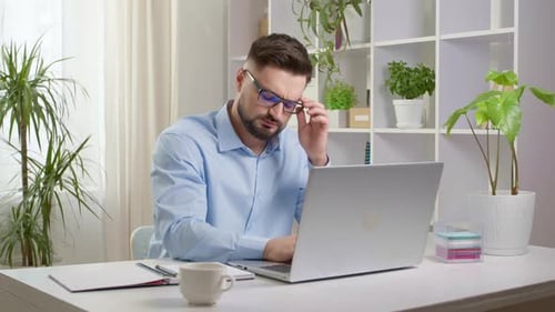 Man Working At Desk, Experiencing Eye Strain