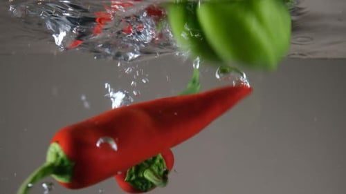 Fresh Peppers Plunging into Water in Slow Motion