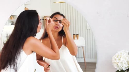 Brunette Woman with Long Straight Dark Hair and Clean Skin Doing Make Up Routine