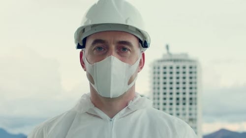 Man Wearing Protective Suit and Mask Stands Outdoors