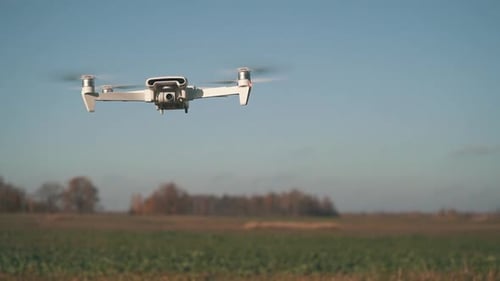 White Drone Hanging in Air or Flying on Nature Background. Slow Motion Shot.