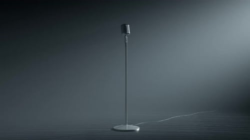 A desaturated vintage microphone on the empty stage. Grey background. Old mic.