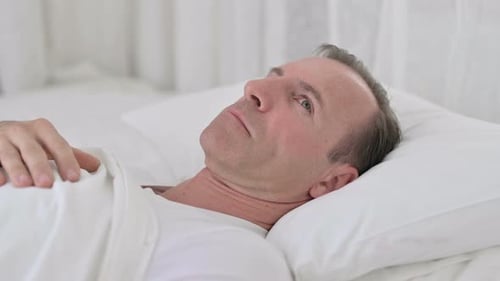 Un homme d'âge moyen inquiet éveillé dans son lit en pensant