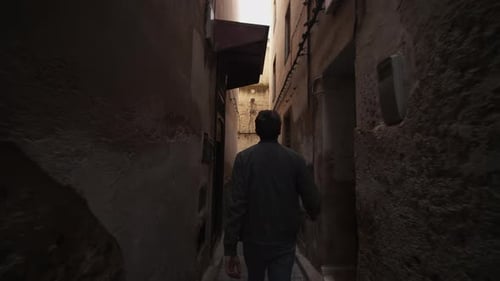 Man Walks Down Narrow Alleyway in an Old City