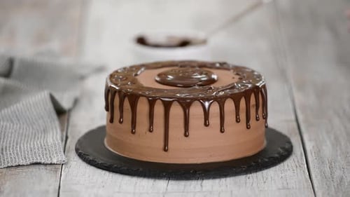 Glazing chocolate cake with melted chocolate. Woman pouring chocolate over cake.