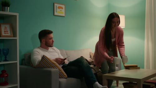 Woman Brings Drinks to Relaxing Man Indoors