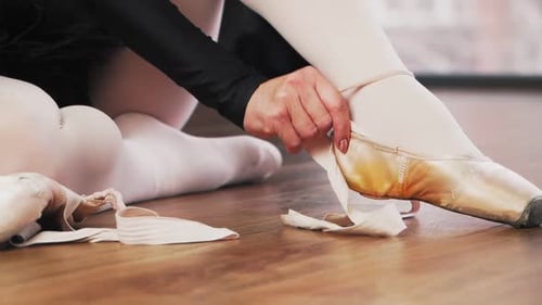 Woman Tying Ribbons on Ballet Pointe Shoes