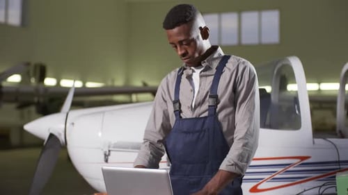 Aircraft Mechanic Working with Computer in Hangar