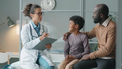 Friendly Doctor Talks to Boy with Father in Office