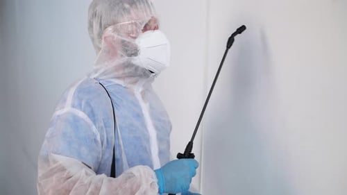 Man in Protective Suit Disinfecting White Wall