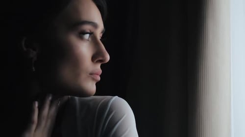 Woman in Robe Looking out of Window