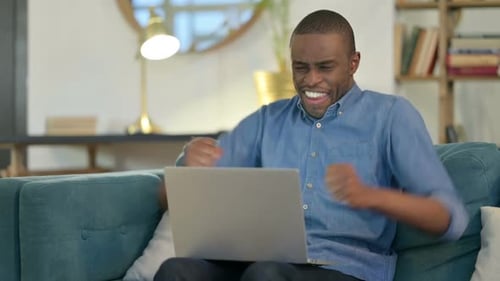 Excited Man Celebrating Success on Laptop at Home