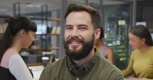 Smiling Man in Office Setting with Coworkers
