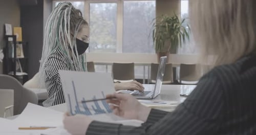 Portrait d'une femme millénaire concentrée et confiante avec des dreadlocks dans un masque facial Covid au travail
