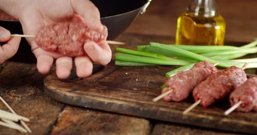 Men's Hands Cook Raw Kebab Sausages on a Stick.