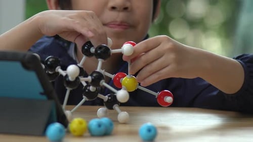 Close Up Of Asian Child Constructing Molecular Model In Science Classroom