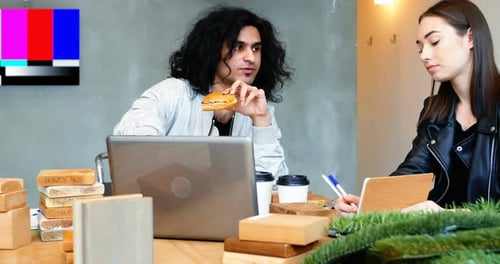 Man Eating Sandwich While Working With Woman