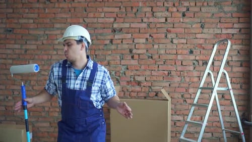 Construction worker with paint roller dances in new house