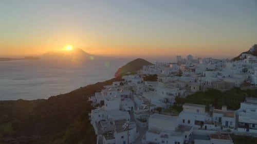 Panela crescente de casas brancas na vila de Plaka e o pôr do sol atrás da montanha