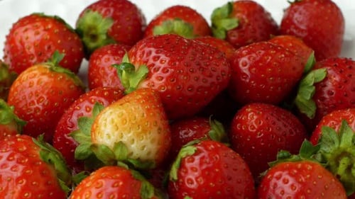 La
hermosa fresa roja madura gira en un plato. Rotación lenta de fresas vista superior de primer plano