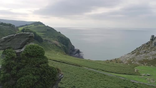 Aerial rotating around a rock stack and pull backwards to reveal the wide expanse of the moor near t