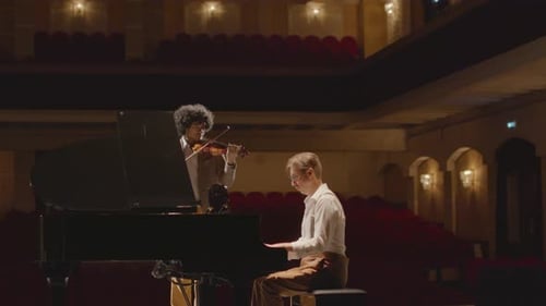 Pianist and Violinist Performing on Music Hall Stage